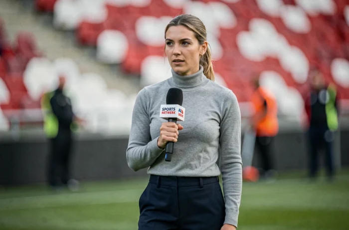 Journaliste sportive réalisant une interview en bord de terrain dans un stade de football