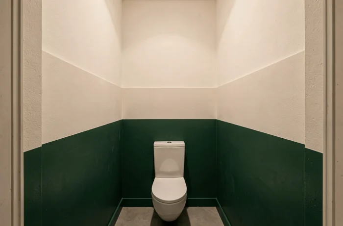 Peinture bicolore avec ligne de coupe haute à 160 cm en vert forêt profond et blanc cassé dans de petites toilettes suspendues allongeant visuellement la hauteur sous plafond